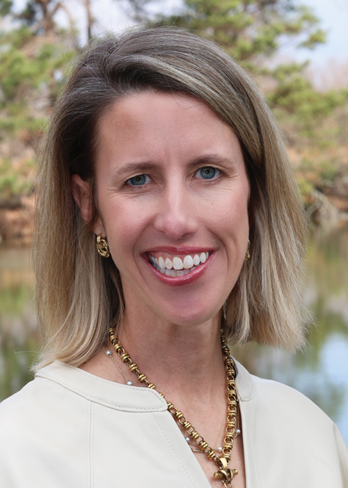 Professional woman with blonde hair smiling outdoors.